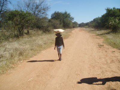 En ung kvinna på väg till kvarnen för att mala mjöl. Säcken bär hon på huvudet.